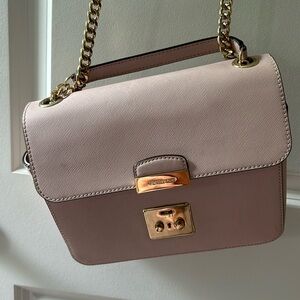 Pink crossbody Michael Kors purse with gold chain.
